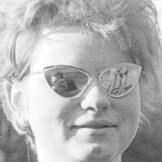 Young woman wearing glasses outdoors in vintage style.