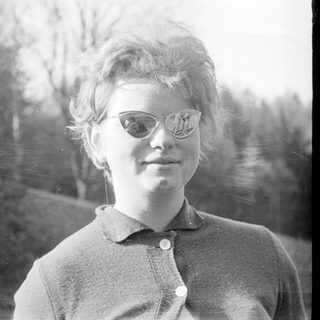 Young woman wearing glasses outdoors in vintage style.