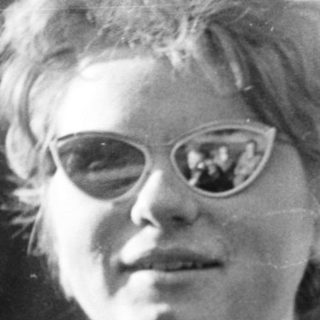 Young person with spiky hair wearing glasses outdoors.