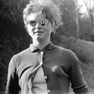 Young person with spiky hair wearing glasses outdoors.