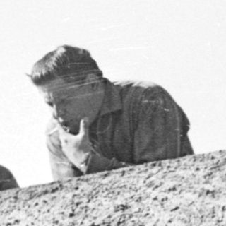 Four people peering over a rocky cliff.