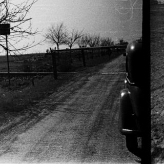 Rural roadside with bare trees, train tracks, and old train car.