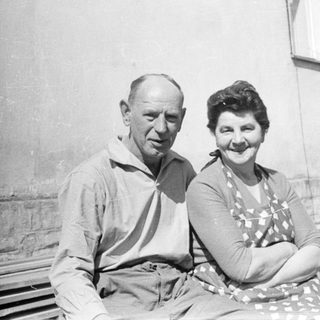 Two elderly couple posing together outdoors in vintage attire.