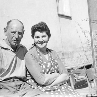 Two elderly couple posing together outdoors in vintage attire.