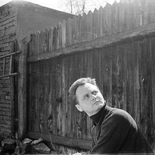 Man leaning against weathered brick wall.