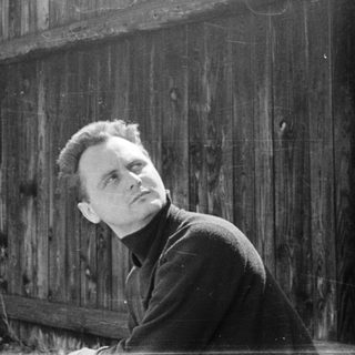 Man leaning against weathered brick wall.