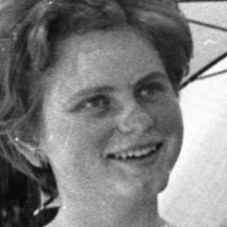 Woman holding open umbrella outdoors, smiling.