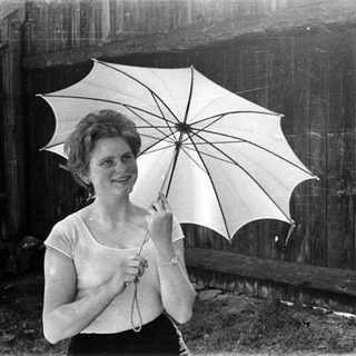 Woman holding open umbrella outdoors, smiling.