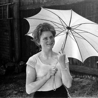 Woman holding open umbrella outdoors, smiling.