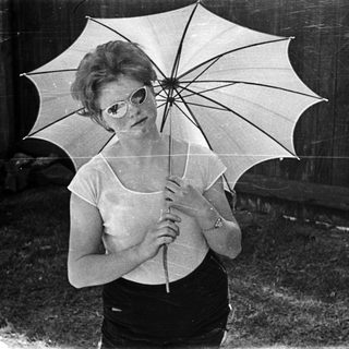Woman holding open umbrella in vintage style pose.