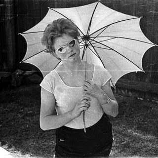 Woman holding open umbrella in vintage style pose.