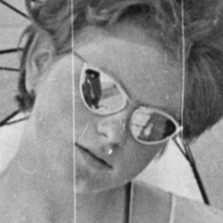 A woman holds a large open umbrella outdoors.