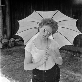 A woman holds a large open umbrella outdoors.