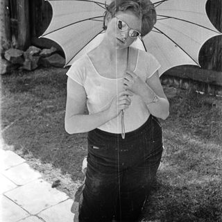 A woman holds a large open umbrella outdoors.