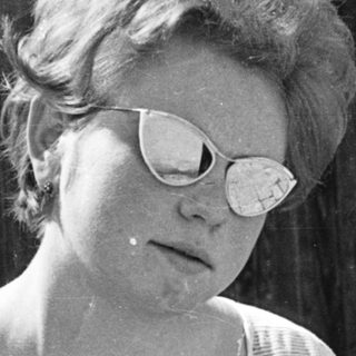 Woman in sunglasses, mid-20th century outdoor portrait.