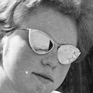 Woman in sunglasses, mid-20th century outdoor portrait.