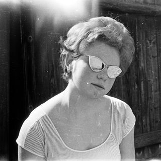 Woman in sunglasses, mid-20th century outdoor portrait.