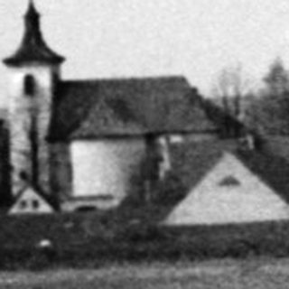 Rural landscape with bare trees, church in distance.