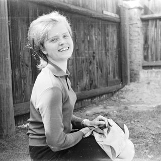 Young girl smiling while holding a cat outdoors.