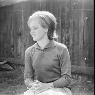 Young woman smiling outdoors near brick wall.