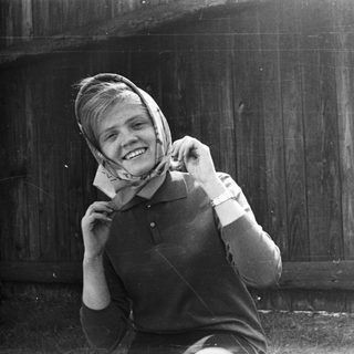 Smiling person adjusting headscarf outdoors.