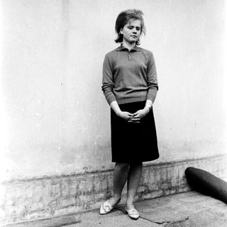 Young woman standing outdoors in 1960s-style clothing.
