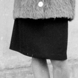 A woman in 1960s-style clothing standing outdoors.