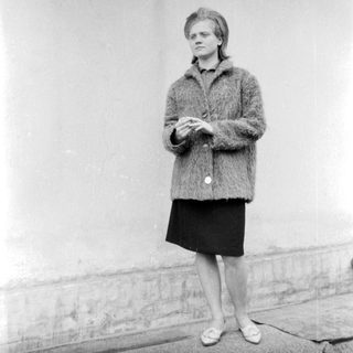 A woman in 1960s-style clothing standing outdoors.