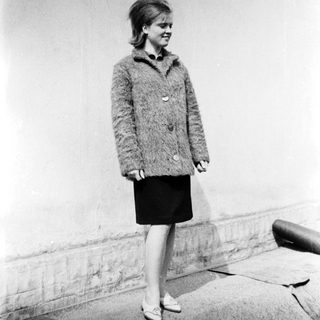 Young woman wearing 1960s-style coat and skirt.