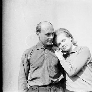 Two people posing closely together outdoors.
