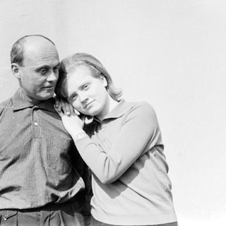 Two people posing closely together outdoors.