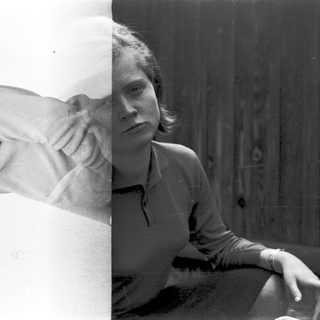 Person sitting by window in vintage-style photograph.