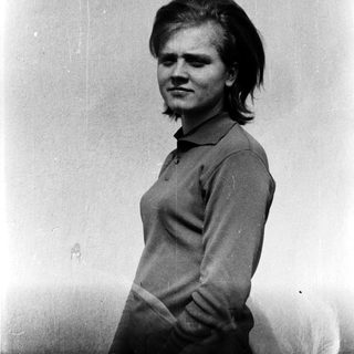 Young person with short hair posing outdoors.