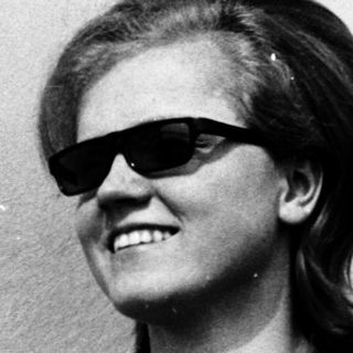 Smiling person wearing sunglasses and polo shirt.
