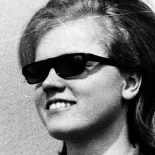 Young person wearing sunglasses and short hair.