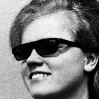 Young person wearing sunglasses and short hair.