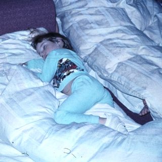 Two people sleeping in a cluttered bedroom.