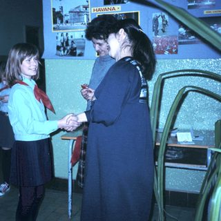 School children shaking hands with adult in uniform.
