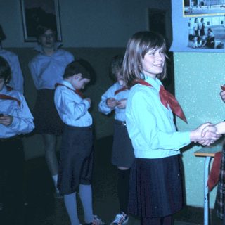 School children shaking hands with adult in uniform.