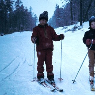 Two children skiing on snow-covered slope.