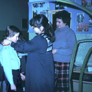 Girl receiving scout uniform patch from adult leader.