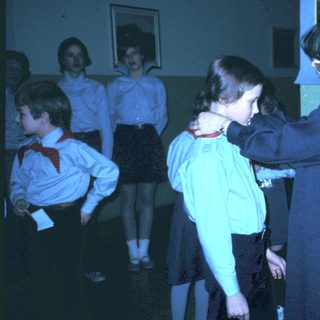 Girl receiving scout uniform patch from adult leader.