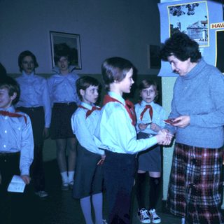 Scouts receiving awards from adult leader indoors.