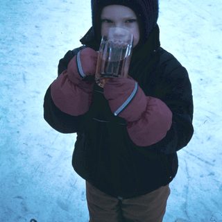Child holding hot drink in winter snow.