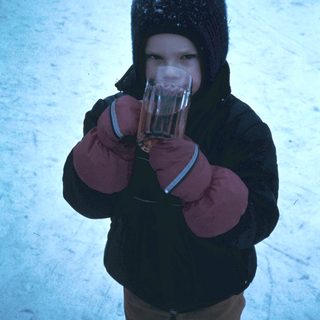 Child holding hot drink in winter snow.