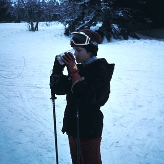 Person skiing in snow, taking a drink.