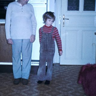 A man and child standing indoors near kitchen.