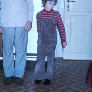 A man and child standing indoors near kitchen.