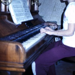 Young person playing a grand piano indoors.