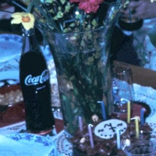 Family celebrating birthday indoors with cake and gifts.